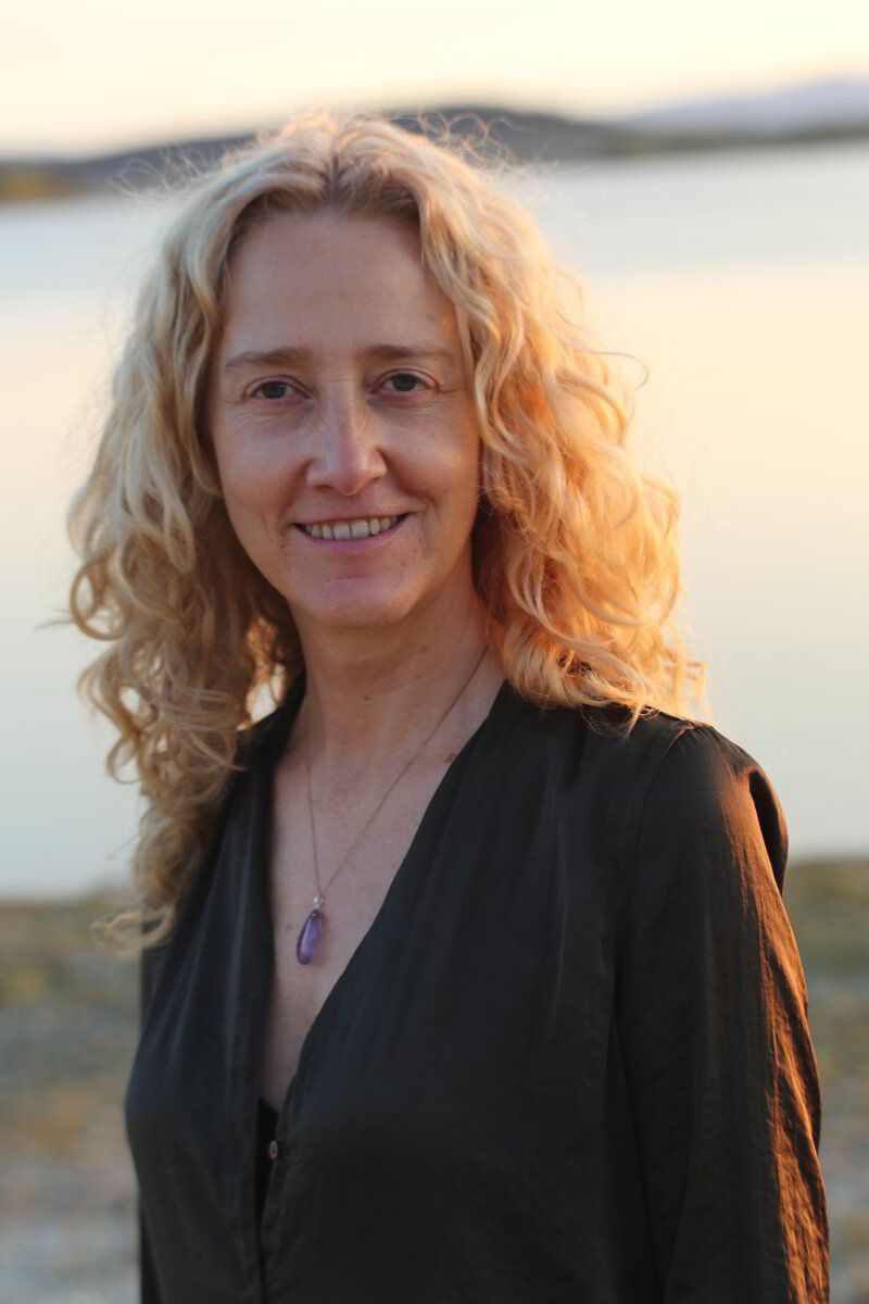 Isabel Madrid sonriendo, con el pelo rizado y el mar al atardecer detrás.